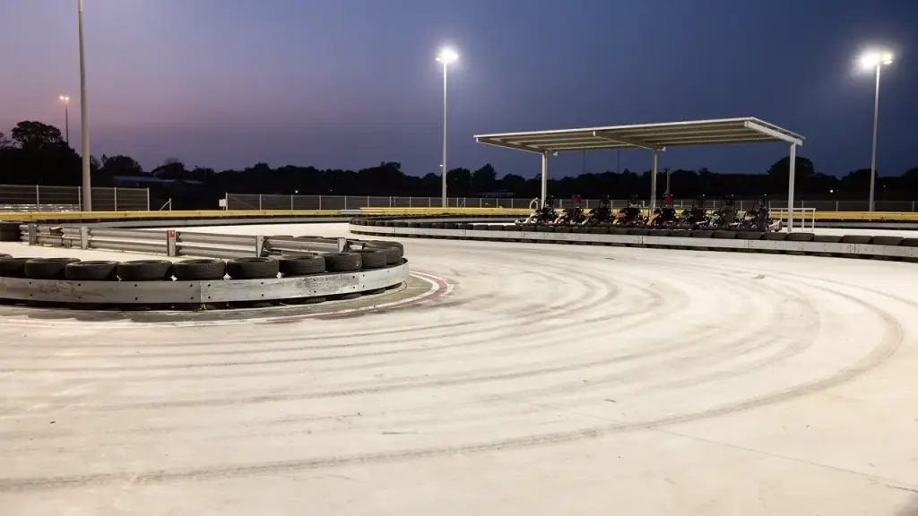 Empty white concrete hairpin lined with a rail of black tires, a covered pit shade behind